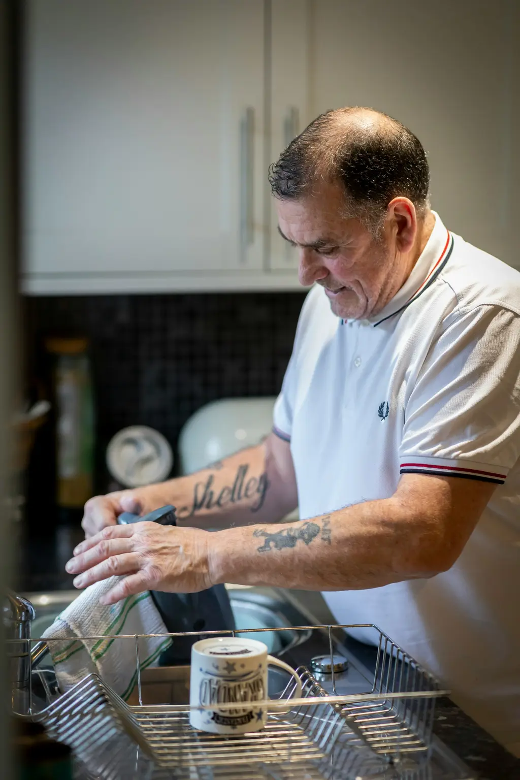 A man washes up at the sink in his kitchen.
